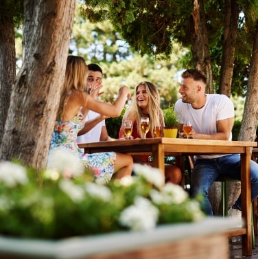 friends at an outside table laughing with drinks